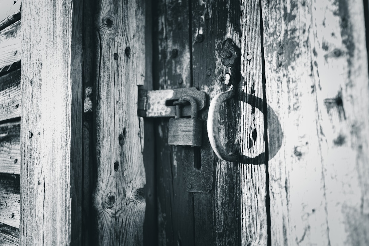 Verrou rouillé sur une porte en bois usée.