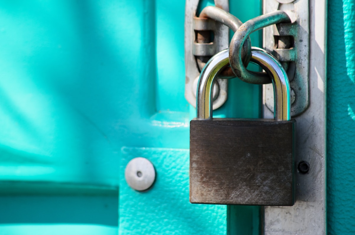 Cadenas verrouillé sur une porte turquoise.