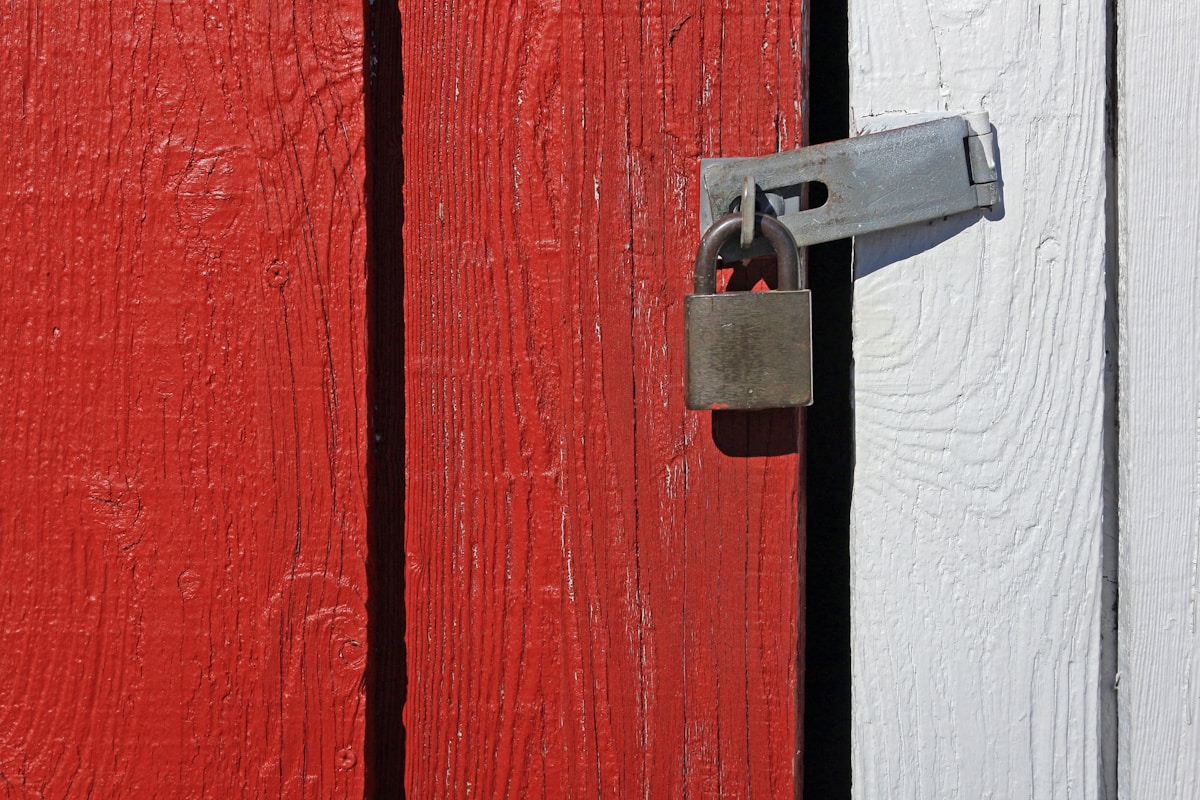 Porte en bois rouge avec cadenas métallique.