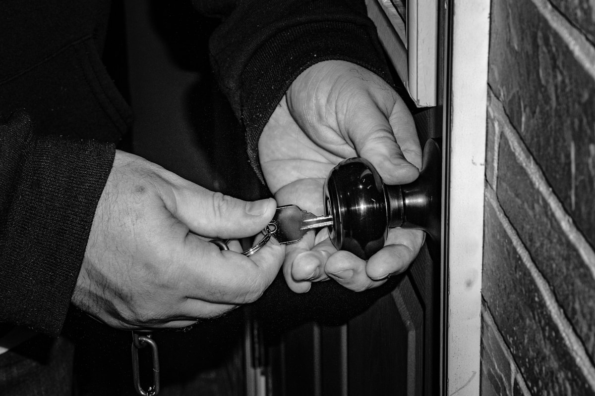 Mains d'un cambrioleur forçant une serrure avec un outil.