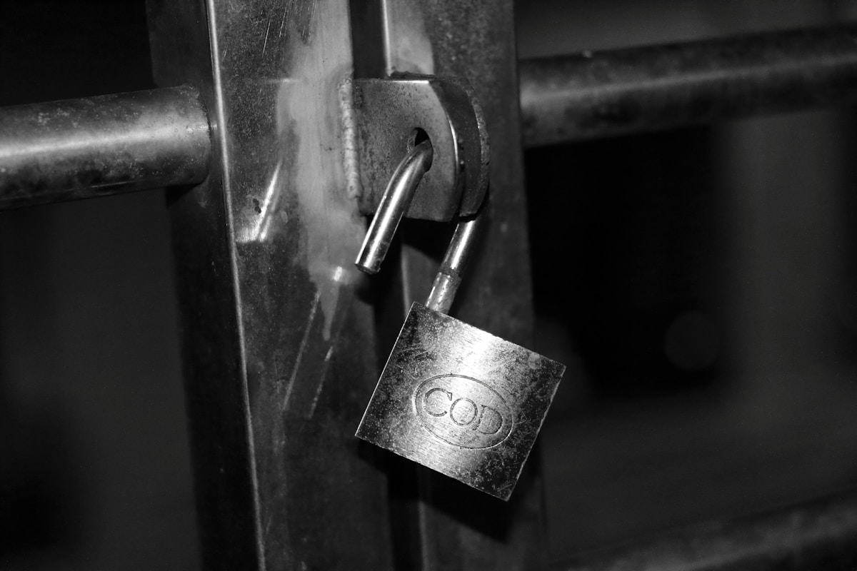 Cadenas rouillé verrouillé sur une porte métallique sombre.