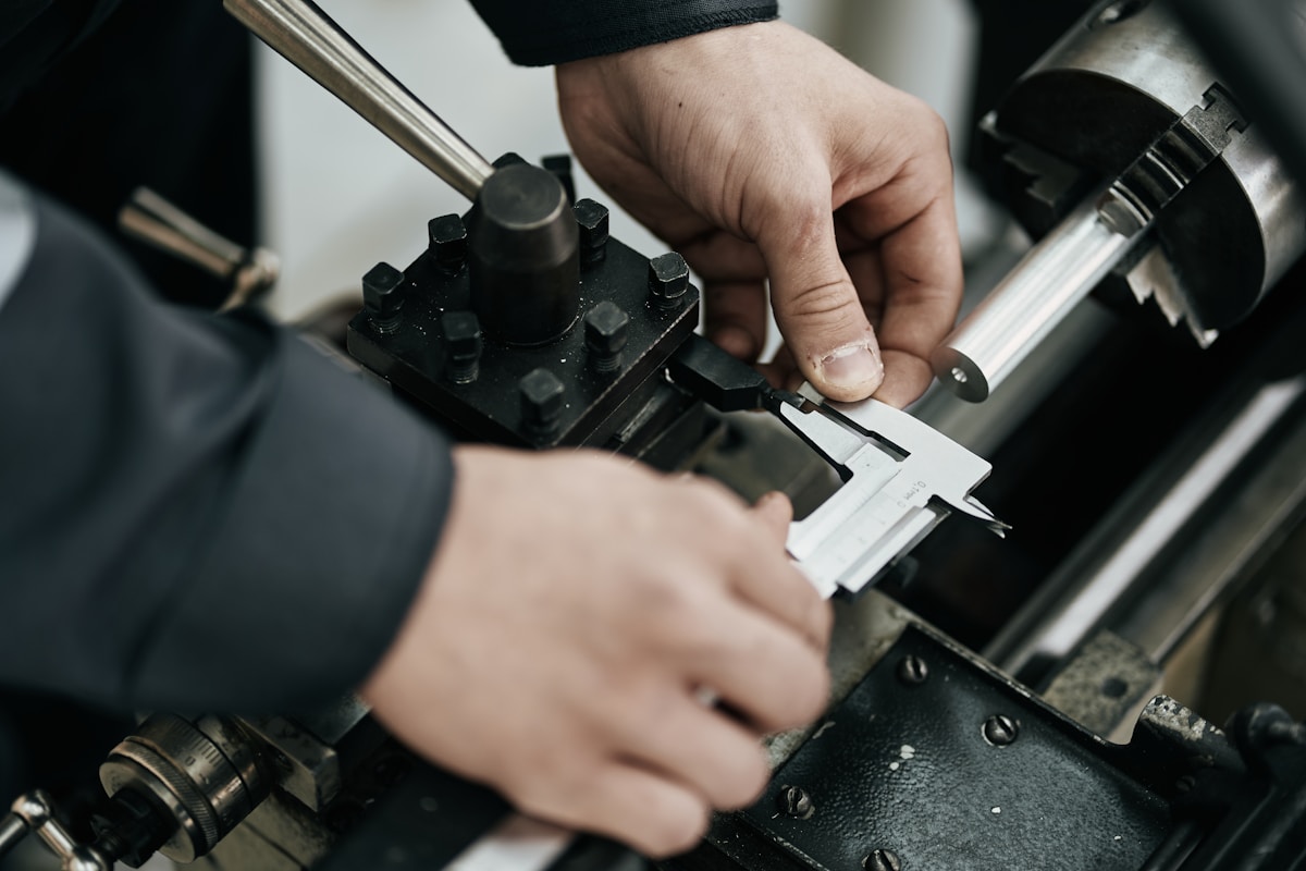 Mains d'un ouvrier manipulant un outil de précision dans un atelier.