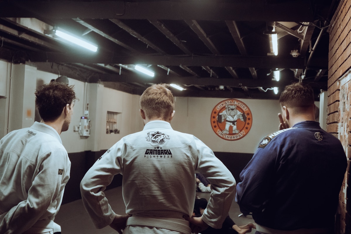 Hommes en tenues de combat dans un gymnase de judo.