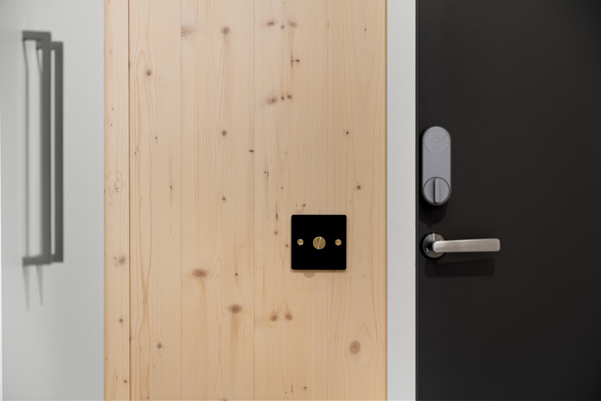 Porte en bois clair avec interrupteur électrique noir.