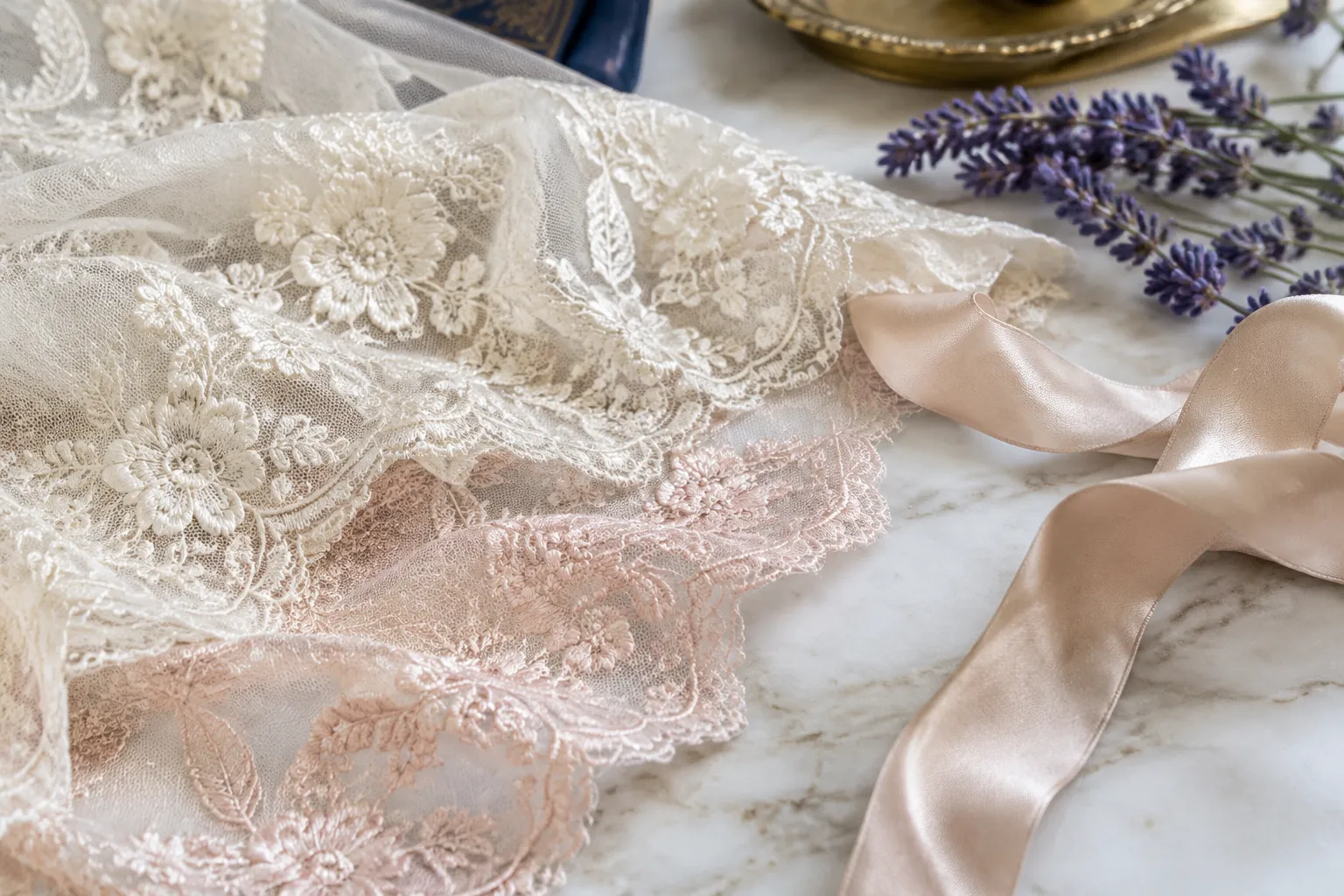 Ivory floral lace, satin ribbon, lavender sprigs on marble countertop