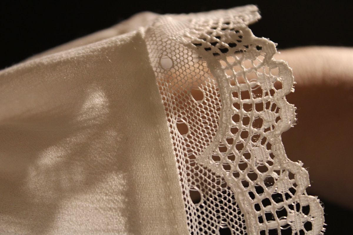 A close up of a person's hand holding a piece of lace
