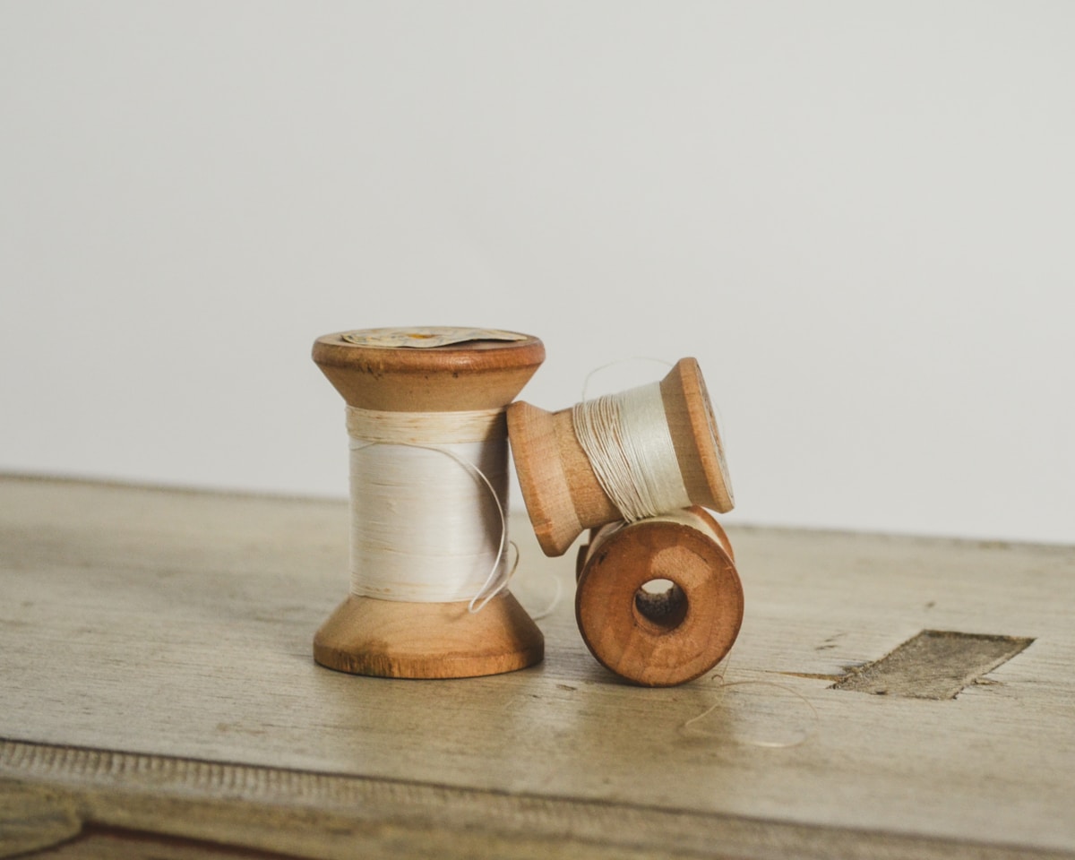 Two vintage wooden spools of white thread