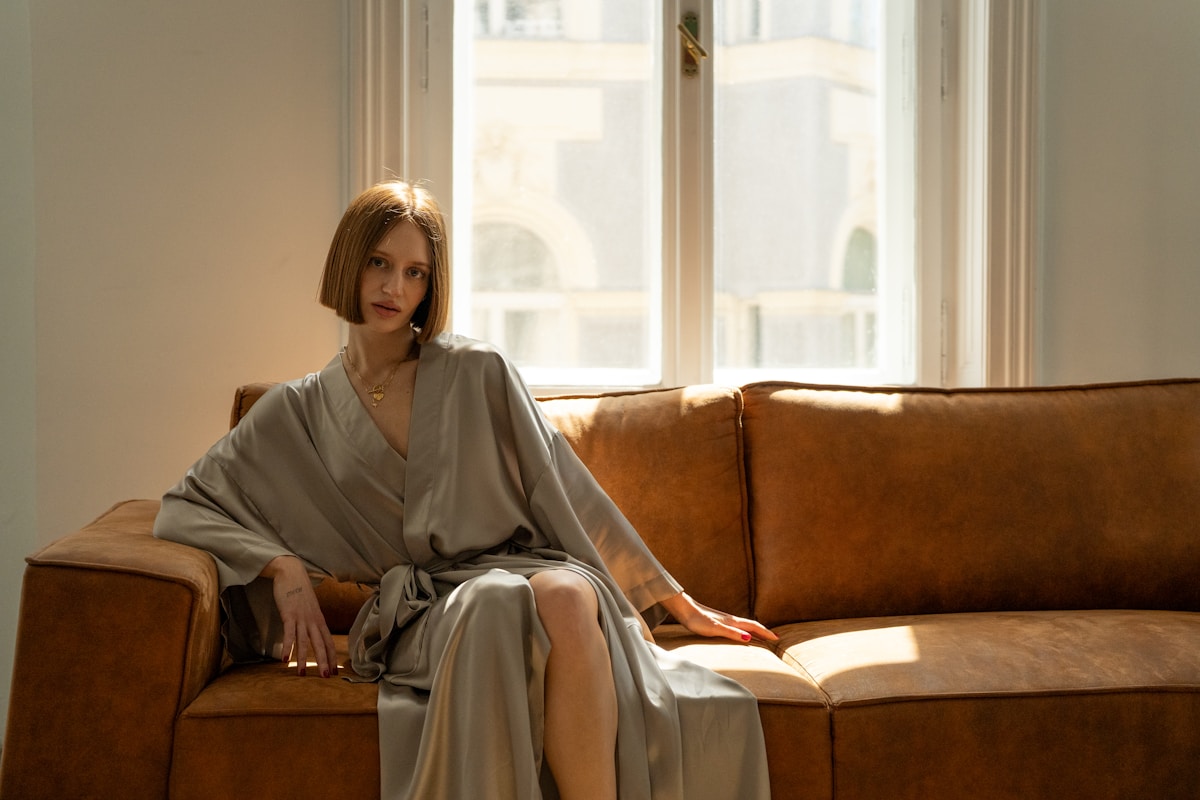 Femme élégante assise sur un canapé dans un intérieur lumineux.
