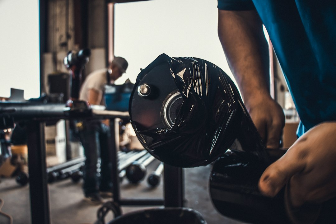 Mains ajustant des poids sur un barbell dans un gym, préparation à une séance de progression renforcement musculaire.
