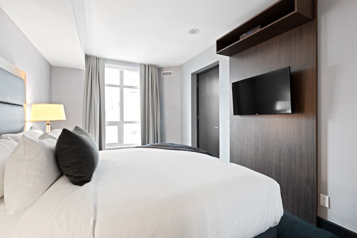 Modernes, geräumiges Hotelzimmer mit Bett, Fernseher und Fenster.