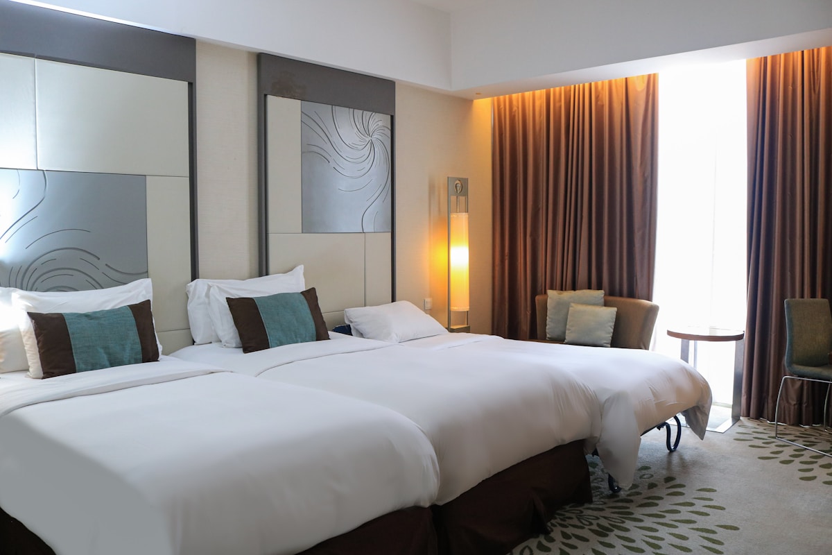 Modernes, luxuriöses Hotelzimmer mit weißen Betten, Vorhängen und Kunstwerken.