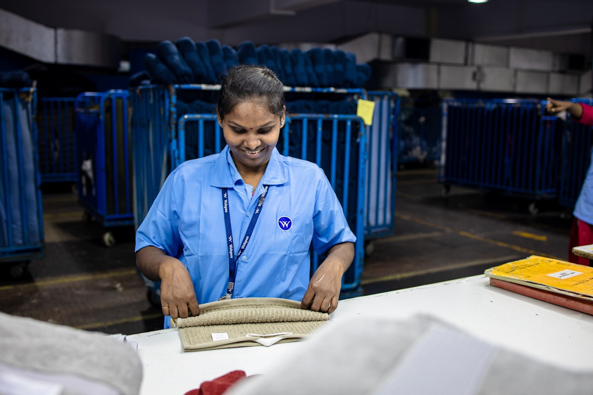 Eine junge Frau in blauer Uniform arbeitet an einem Schreibtisch in einem Lagerraum.