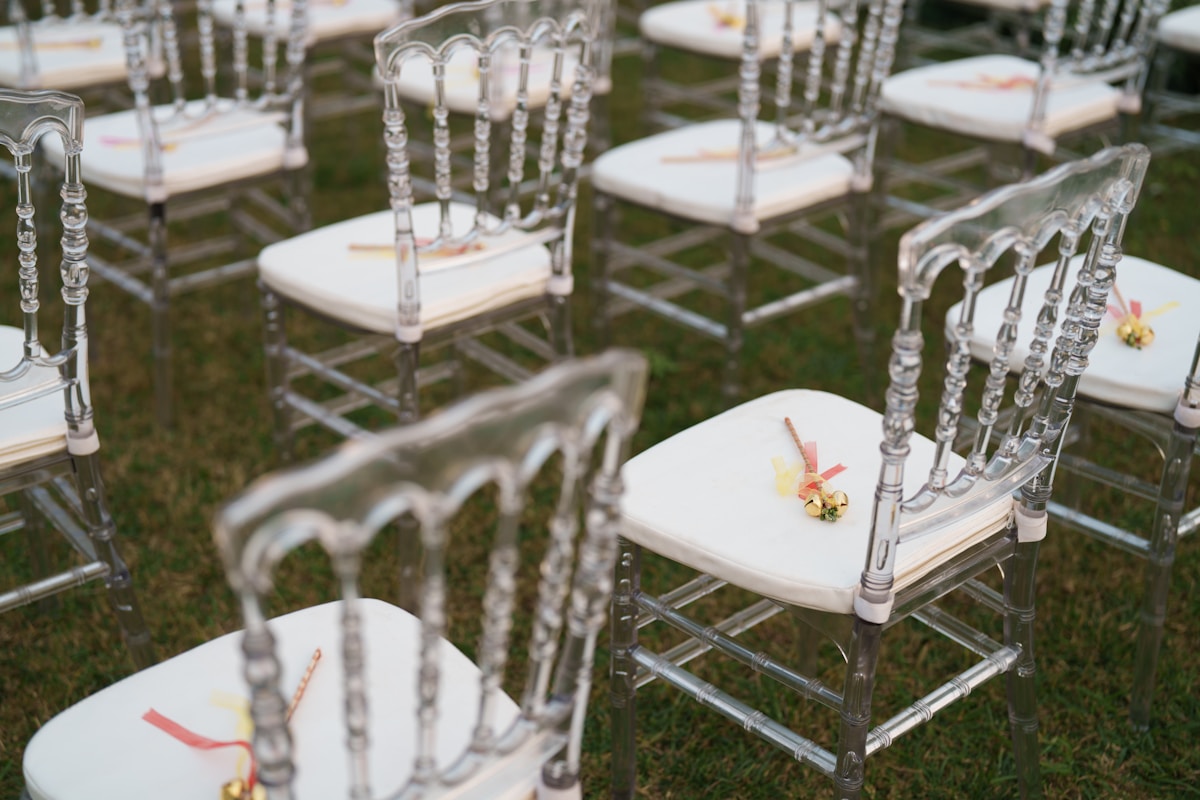 Chaises transparentes élégantes avec décorations florales pour une cérémonie.