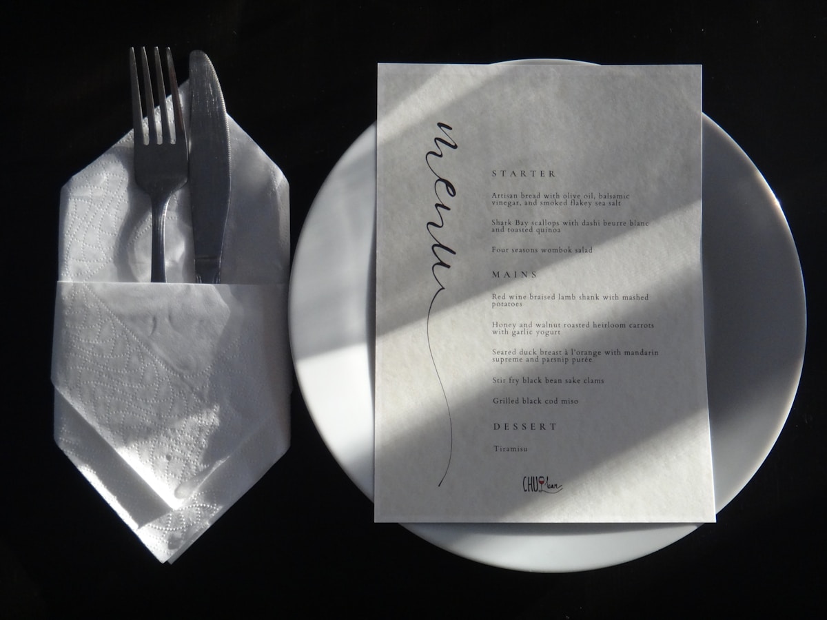 Menu de restaurant avec couverts sur une assiette blanche.