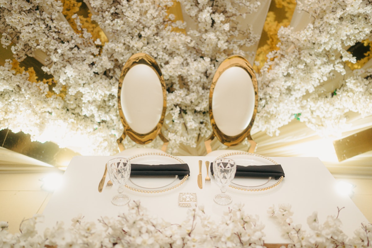 Miroirs dorés, verres de cristal, bougeoirs sur une table fleurie.