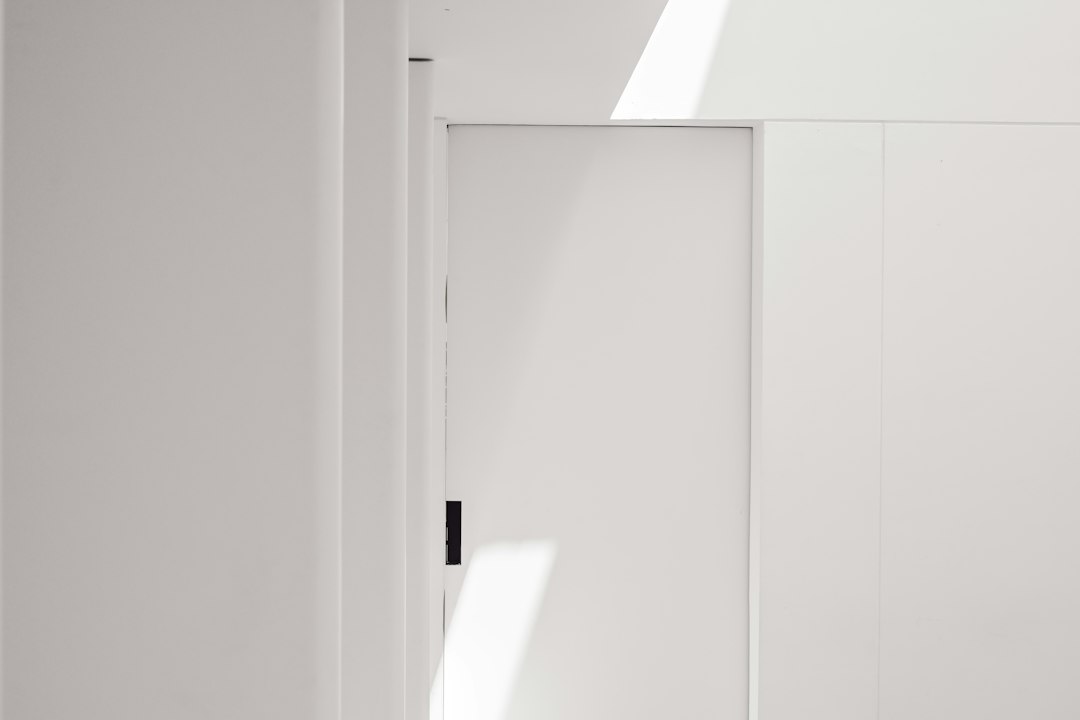 Intérieur minimaliste blanc, porte, ombres de soleil : Renforcement de baie coulissante 2026 Guide complet sécuriser accès