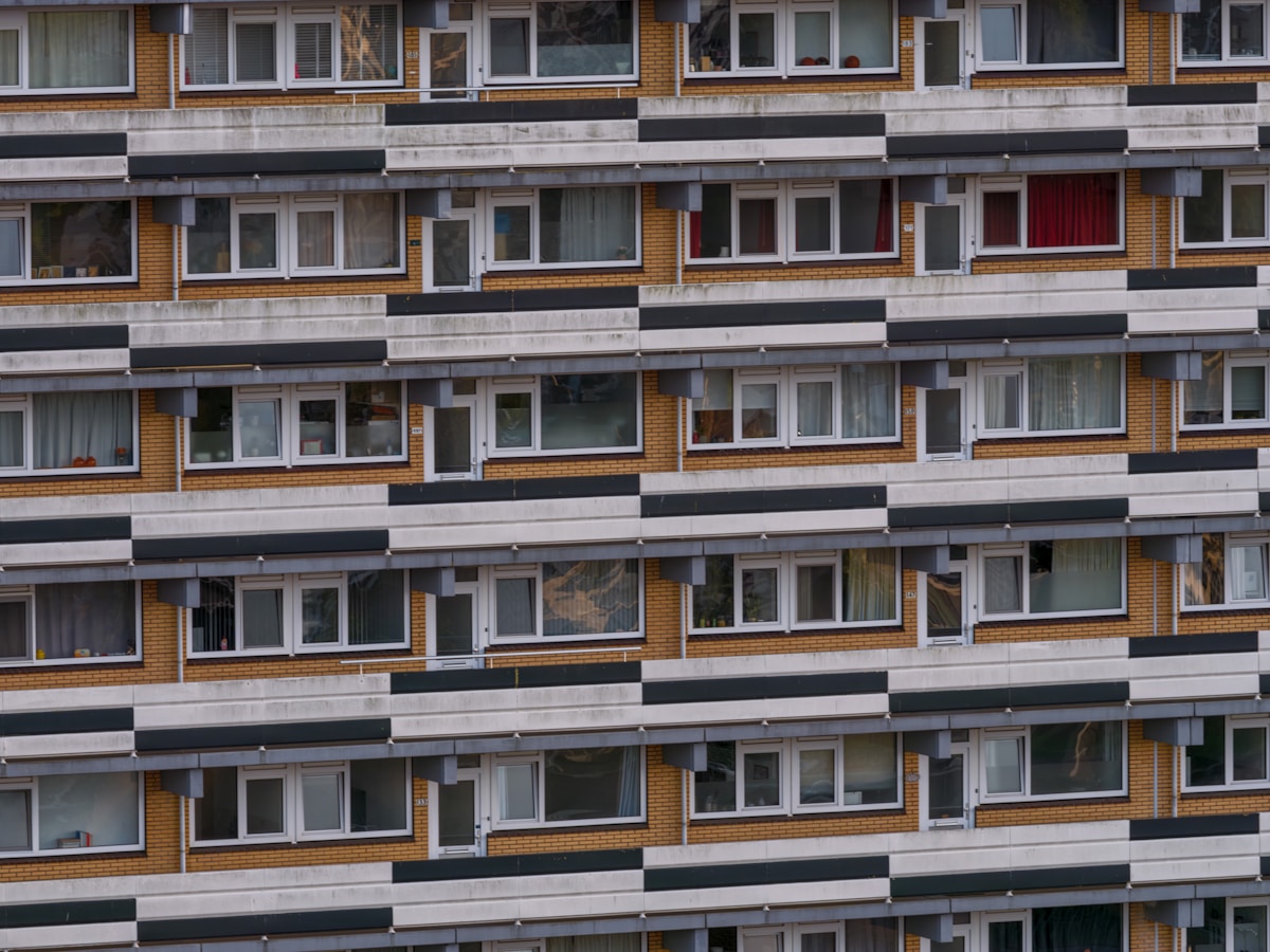 Immeuble d'appartements aux façades bicolores, fenêtres et balcons.