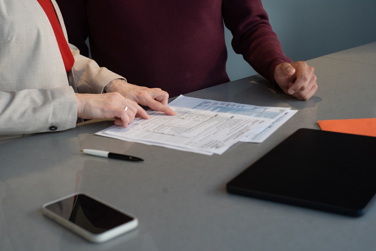 Deux personnes examinent attentivement des documents sur un bureau.