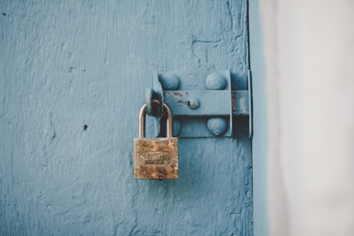 Cadenas rouillé sur une porte en bois bleu délavé.