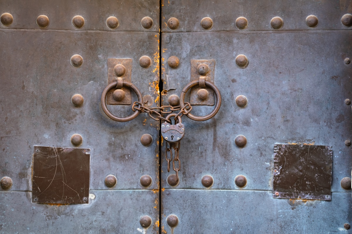 Porte en métal ancienne avec verrou et anneaux de tirage.