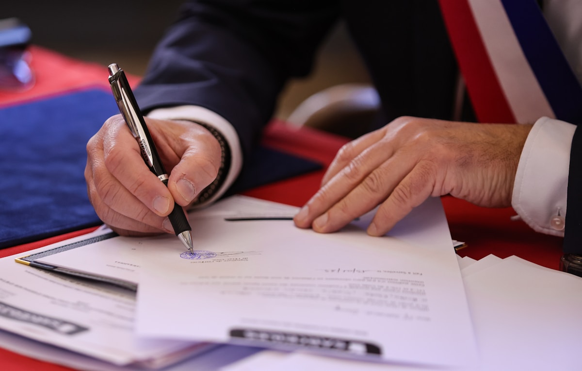 Mains d'un homme signant un document officiel avec un stylo.