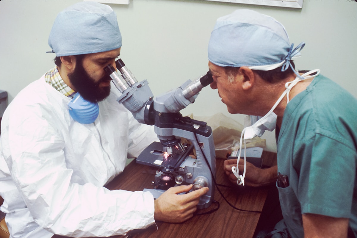 Deux médecins en blouse blanche examinent un patient à l'aide d'un microscope.