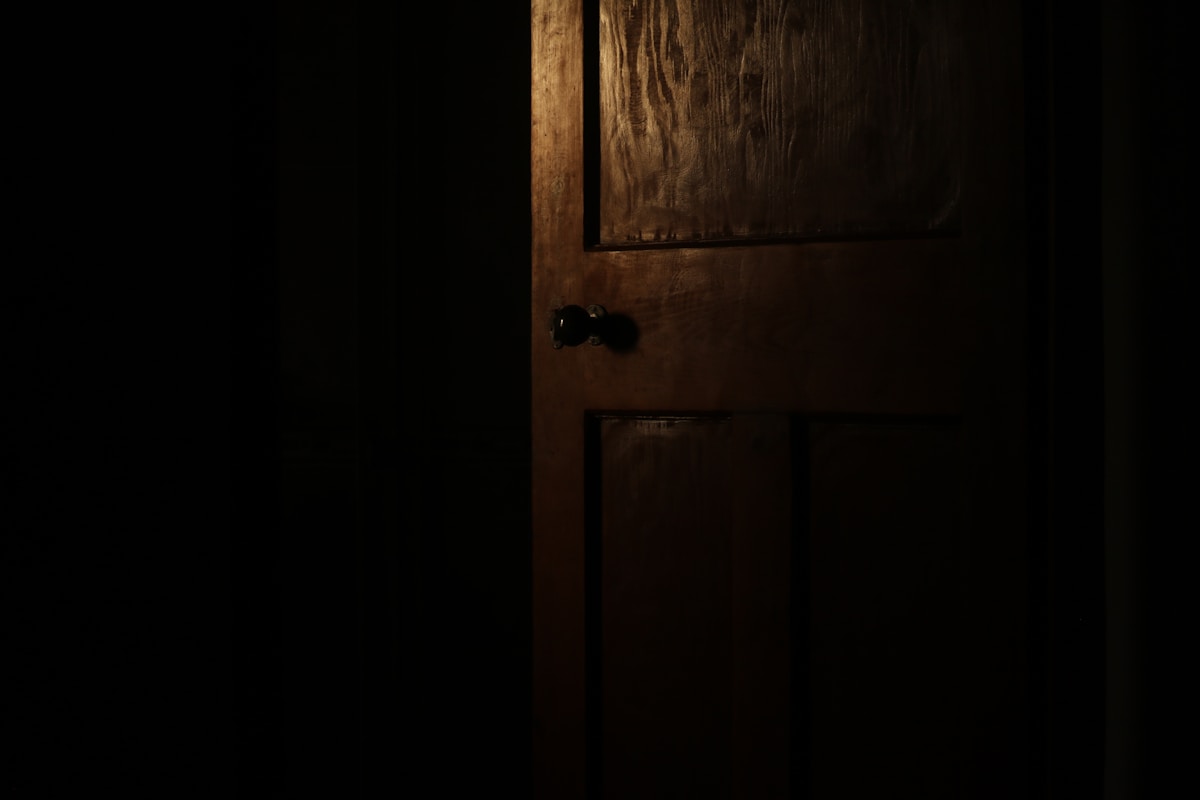 Porte en bois sombre et ancienne dans un environnement sombre.
