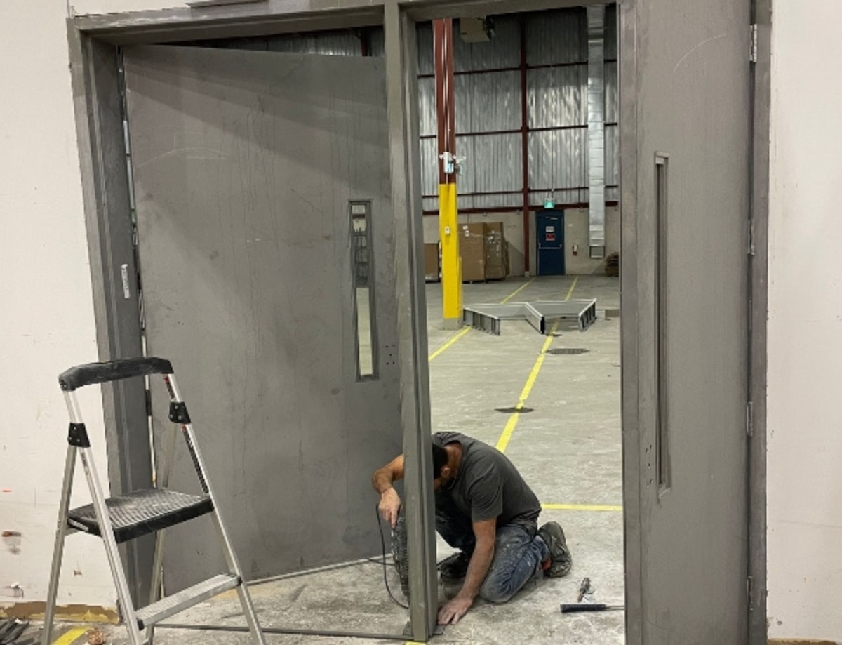 Ouvrier installant une porte de garage dans un entrepôt.
