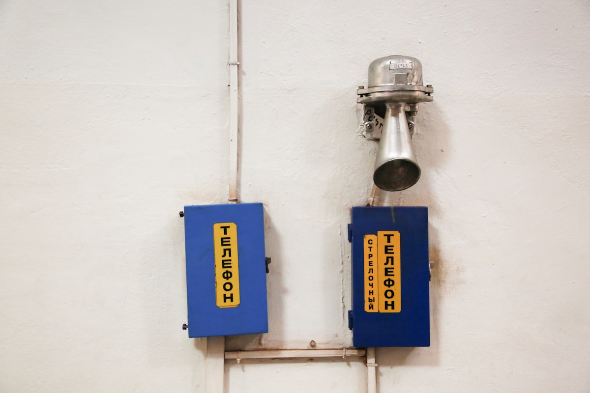Deux boîtiers bleus avec des étiquettes jaunes indiquant "Téléphone" et "Interphone".
