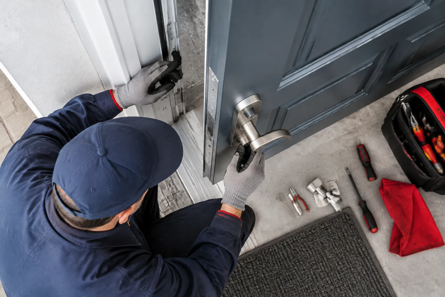 Technicien installant une poignée sur une porte d’entrée grise