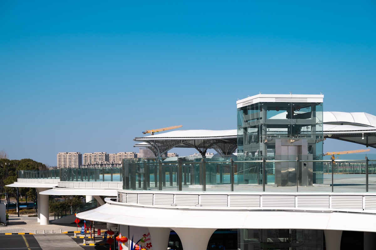 Bâtiment moderne en verre et acier avec terrasse surplombant la ville.
