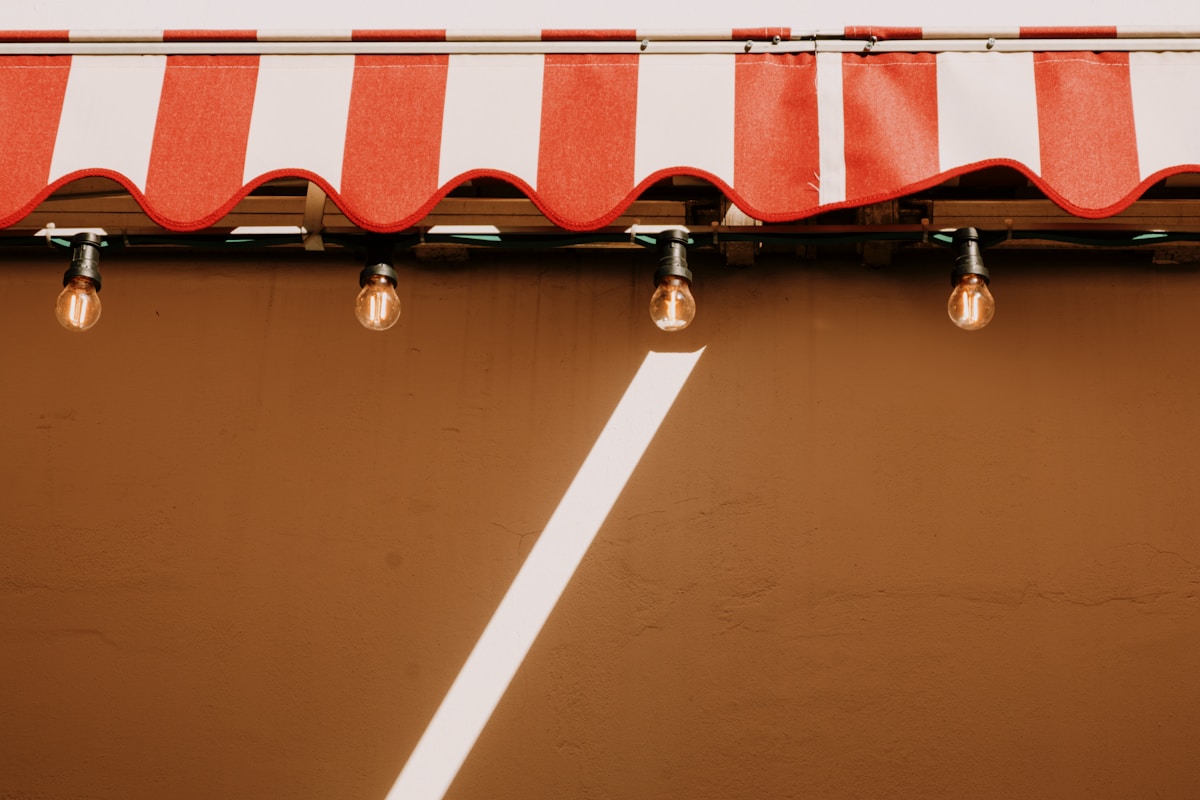 Rideau rayé rouge et blanc avec des ampoules suspendues.