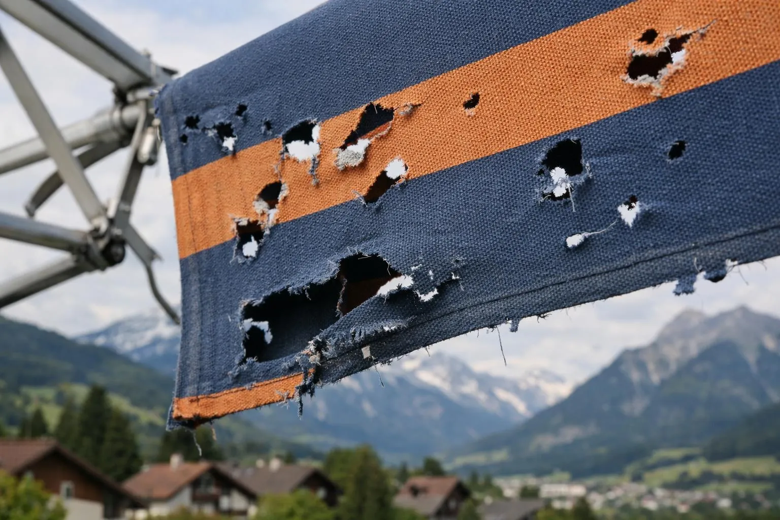 Drapeau déchiré et usé suspendu avec paysage montagneux à l'arrière-plan.