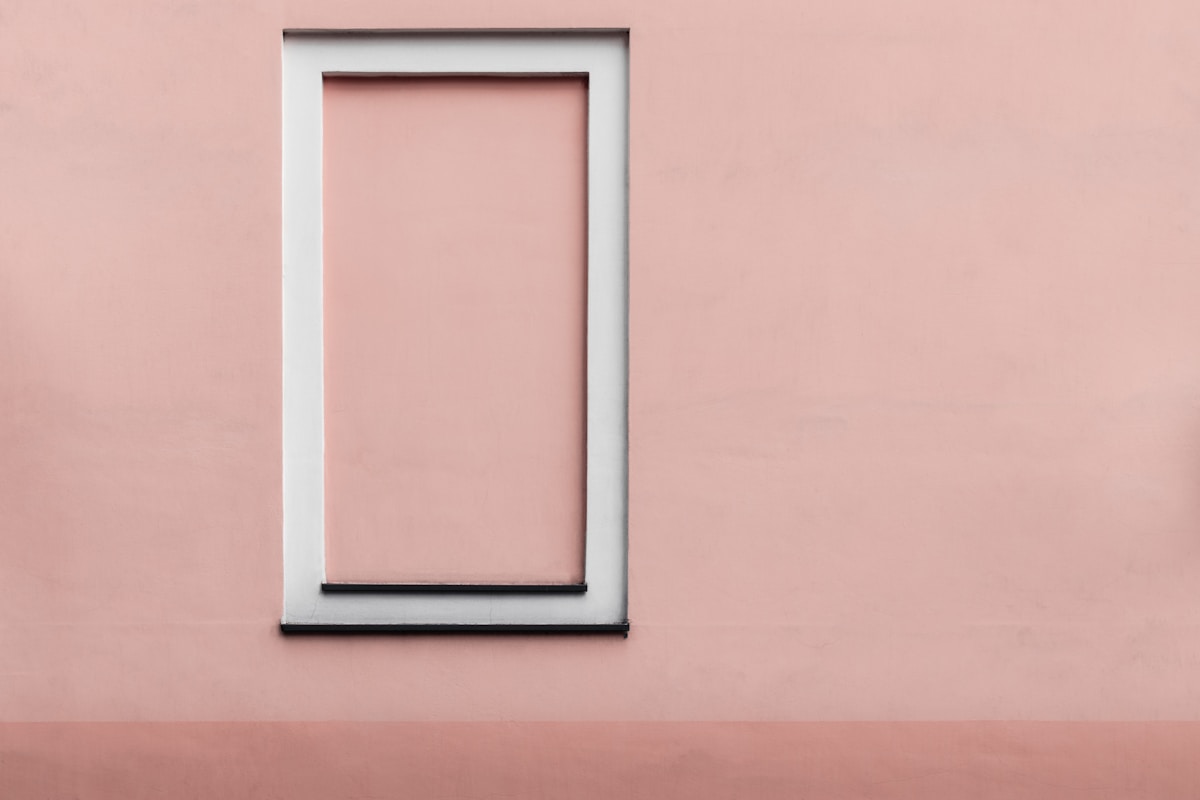 Cadre blanc sur un mur rose, minimaliste et épuré.