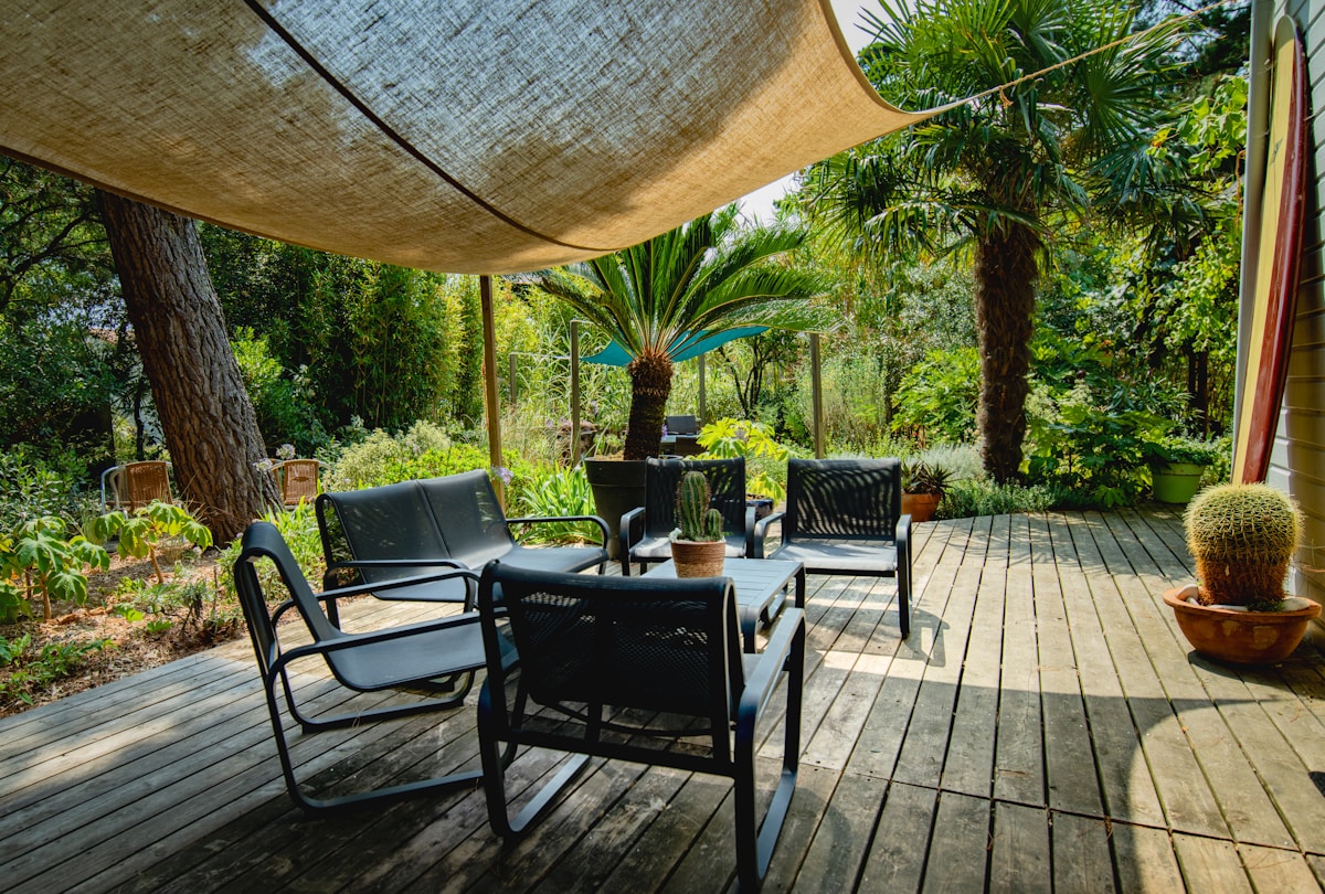 Terrasse ombragée avec mobilier de jardin dans un environnement tropical luxuriant.