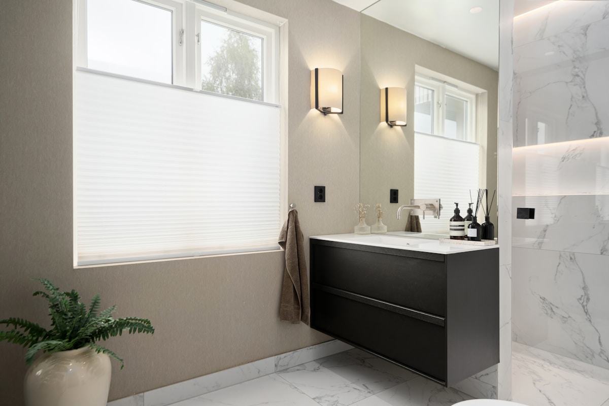 Salle de bain moderne avec meuble noir et marbre blanc.