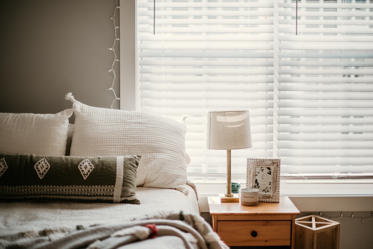 Chambre confortable avec fenêtre, lampe et coussins décoratifs.