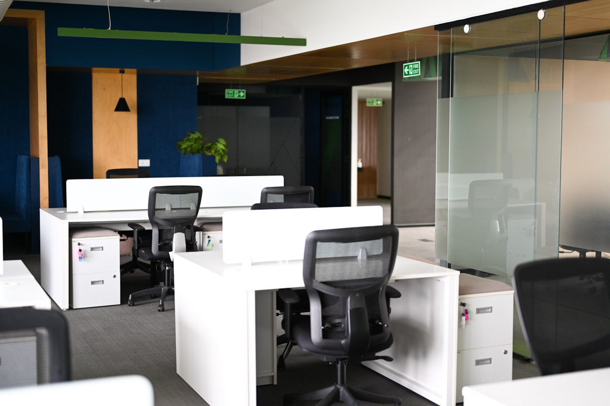 Modern office interior with white desks and black chairs.