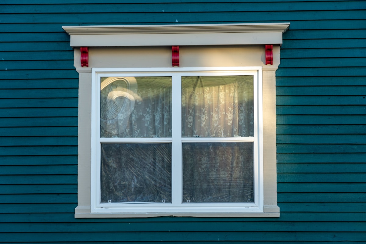Window with a decorative trim on a teal building.