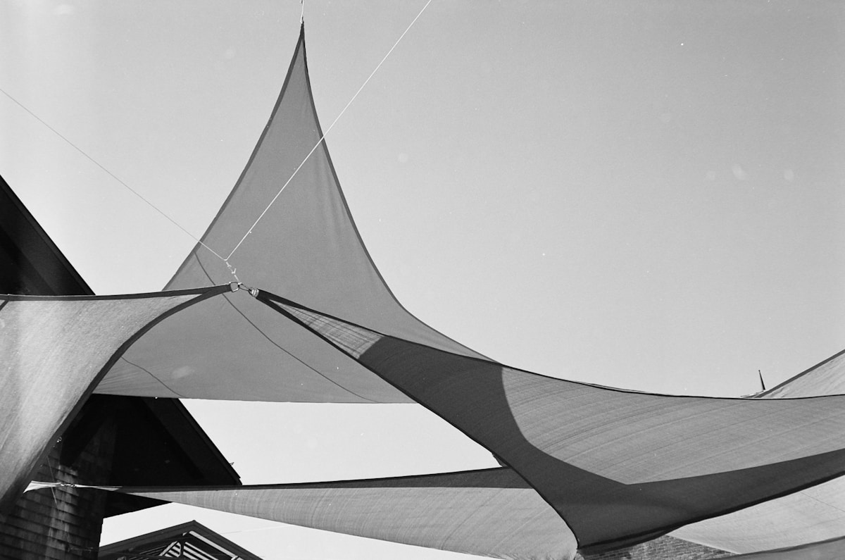 Voiles triangulaires tendues dans le ciel, structure géométrique abstraite.