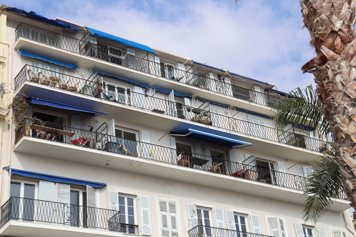 Immeuble d'appartements avec balcons et stores bleus.
