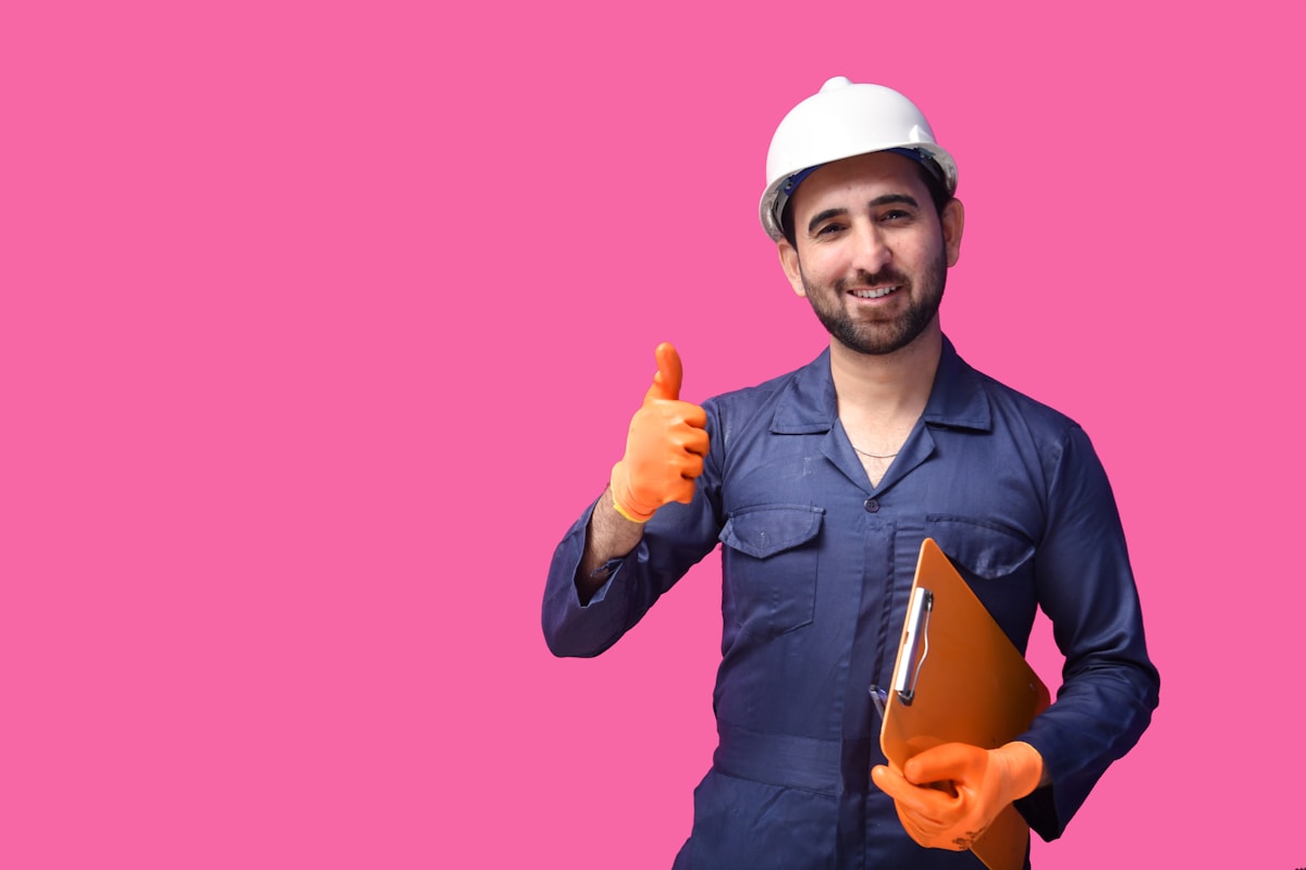 Ouvrier en uniforme bleu avec casque de sécurité donnant le pouce levé.