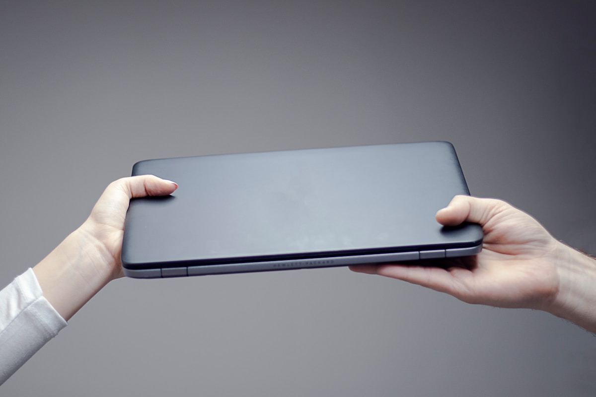 Ordinateur portable noir tenu dans les mains.