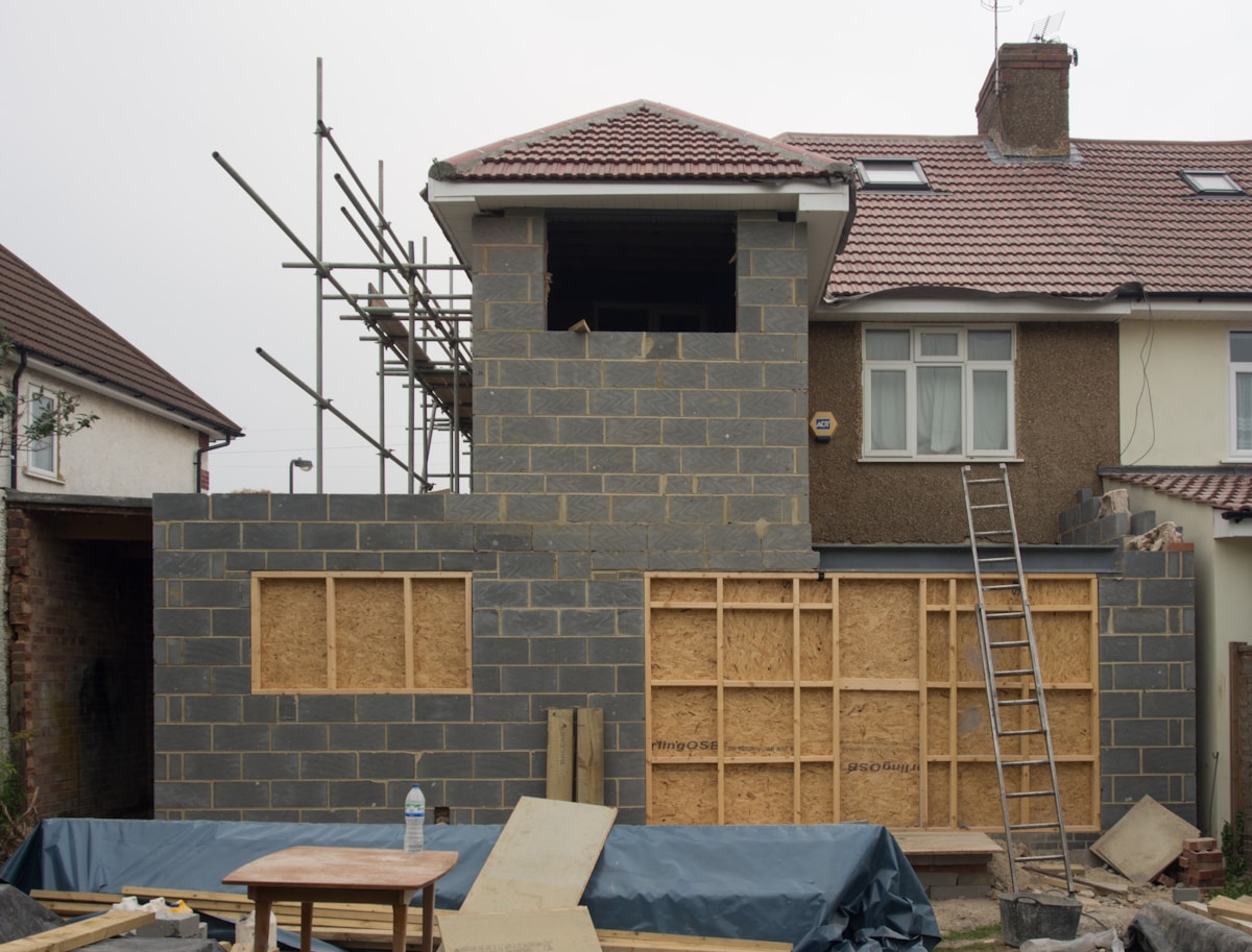 Maison en construction avec échafaudage et matériaux de construction.