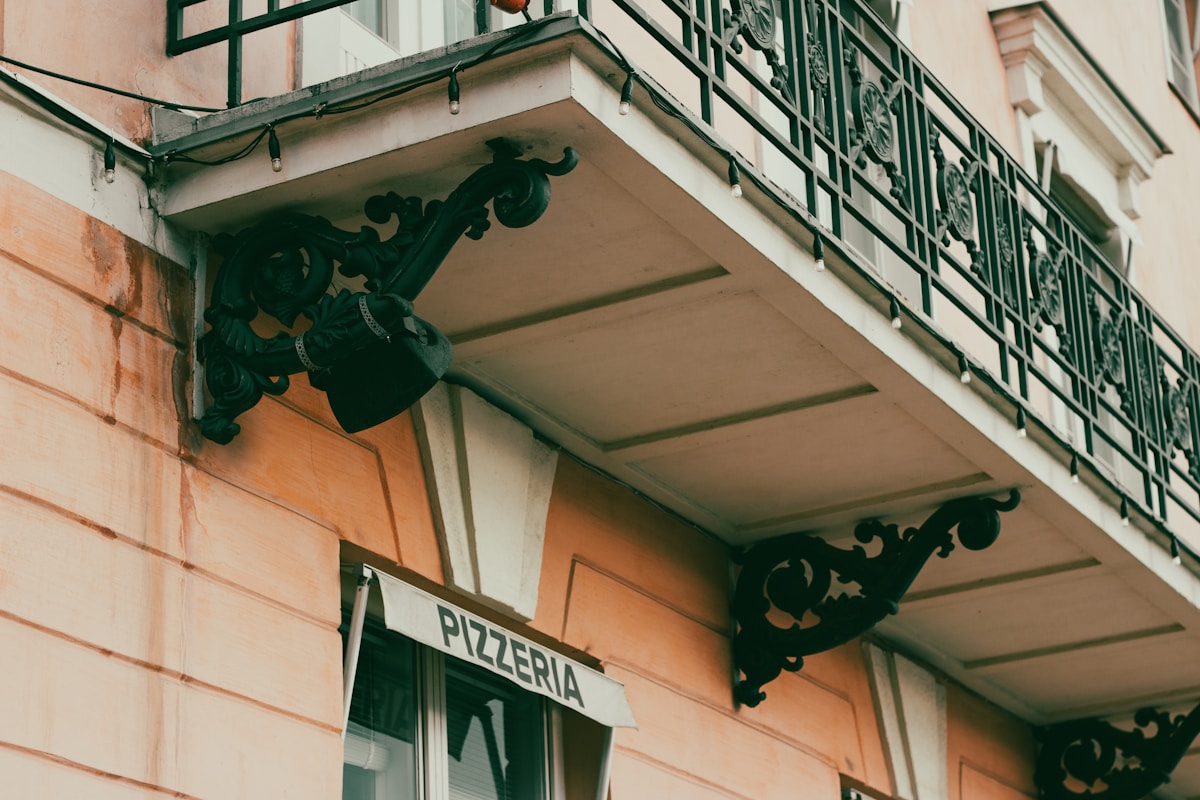 Façade d'un bâtiment avec enseigne "Pizzeria" et décorations ornementales.