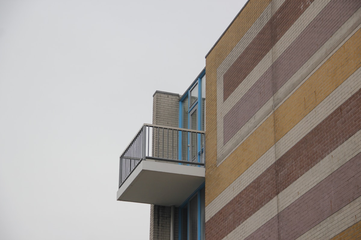 Bâtiment en briques avec balcon et fenêtres bleues.