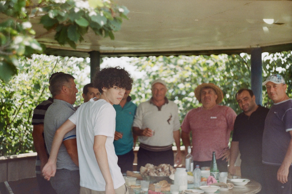 Groupe d'amis réunis pour un repas convivial dans un jardin verdoyant.