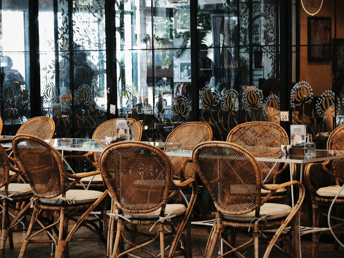 Chaises en rotin dans un café avec décor tropical.