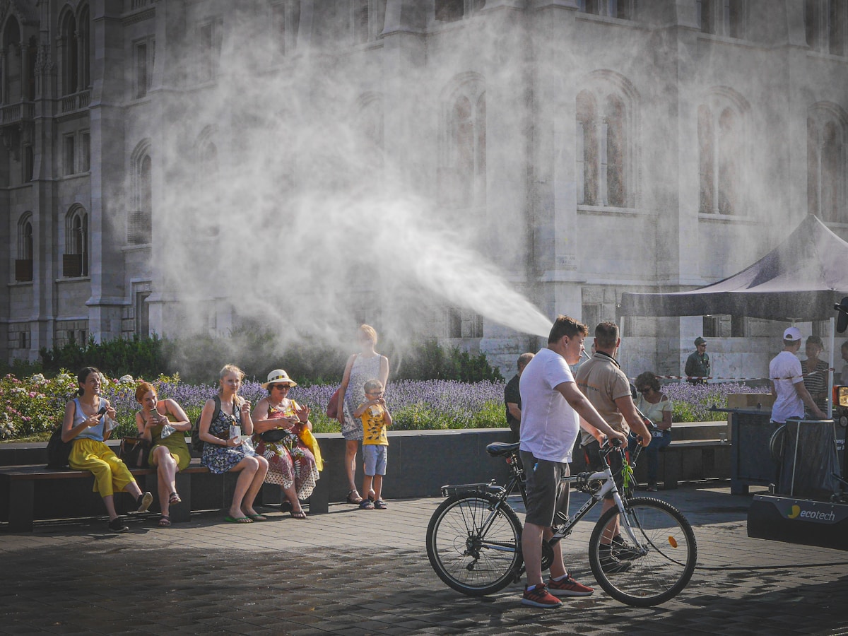 Personnes se rafraîchissant dans la brume d'un parc urbain.