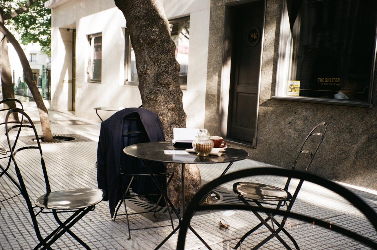 Table et chaises dans une rue ombragée.